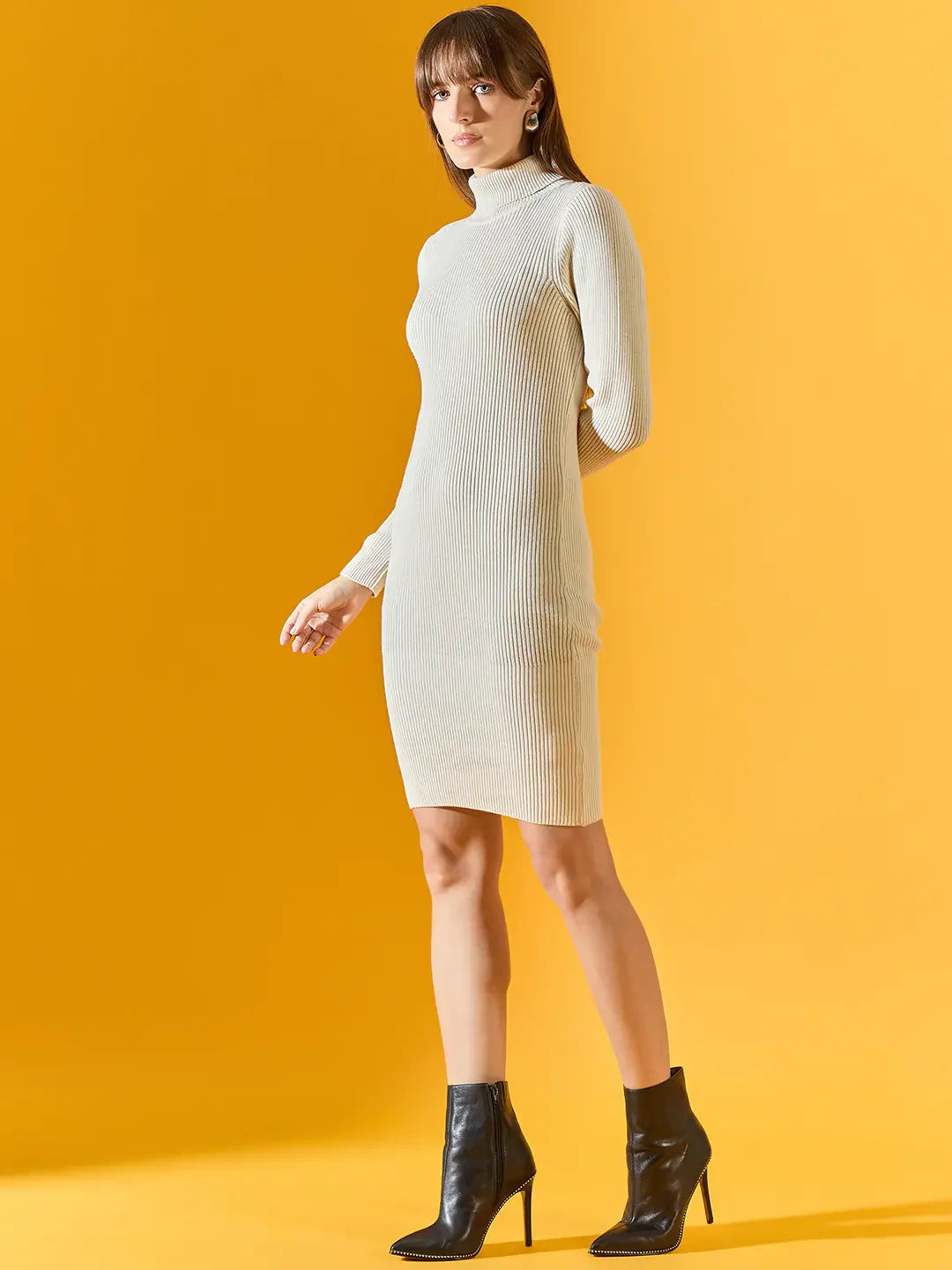 Woman wears a 98degreenorth off-white ribbed bodycon turtleneck dress, paired with black ankle boots on yellow backdrop.