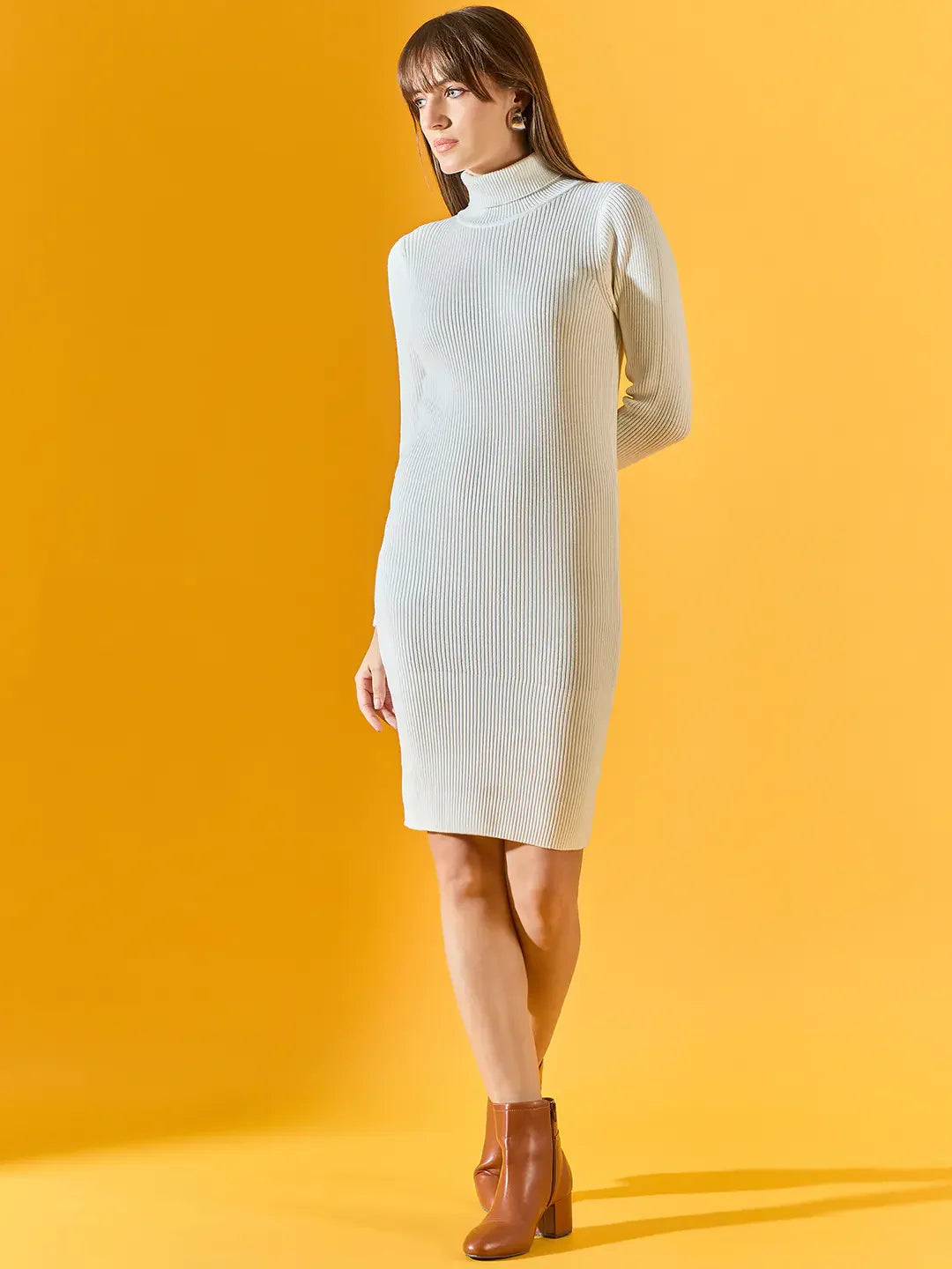 Woman in a 98degreenorth Ribbed Knitted Bodycon White Sweater Dress and brown ankle boots on a yellow background.