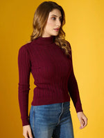 Woman in 98degreenorth’s rosewood ribbed turtleneck sweater and blue jeans stands against a yellow background.