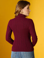 Woman in 98degreenorth Rosewood Ribbed Turtleneck Sweater and blue jeans stands, back to camera, on yellow backdrop.