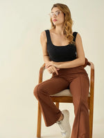 Woman with wavy hair in glasses and a black top wears 98degreenorth rust flared bootcut cotton stretchable trousers.