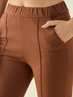Close-up of a person wearing 98degreenorth Women’s Rust Flared Bootcut Cotton Stretchable Trousers, hand in pocket.