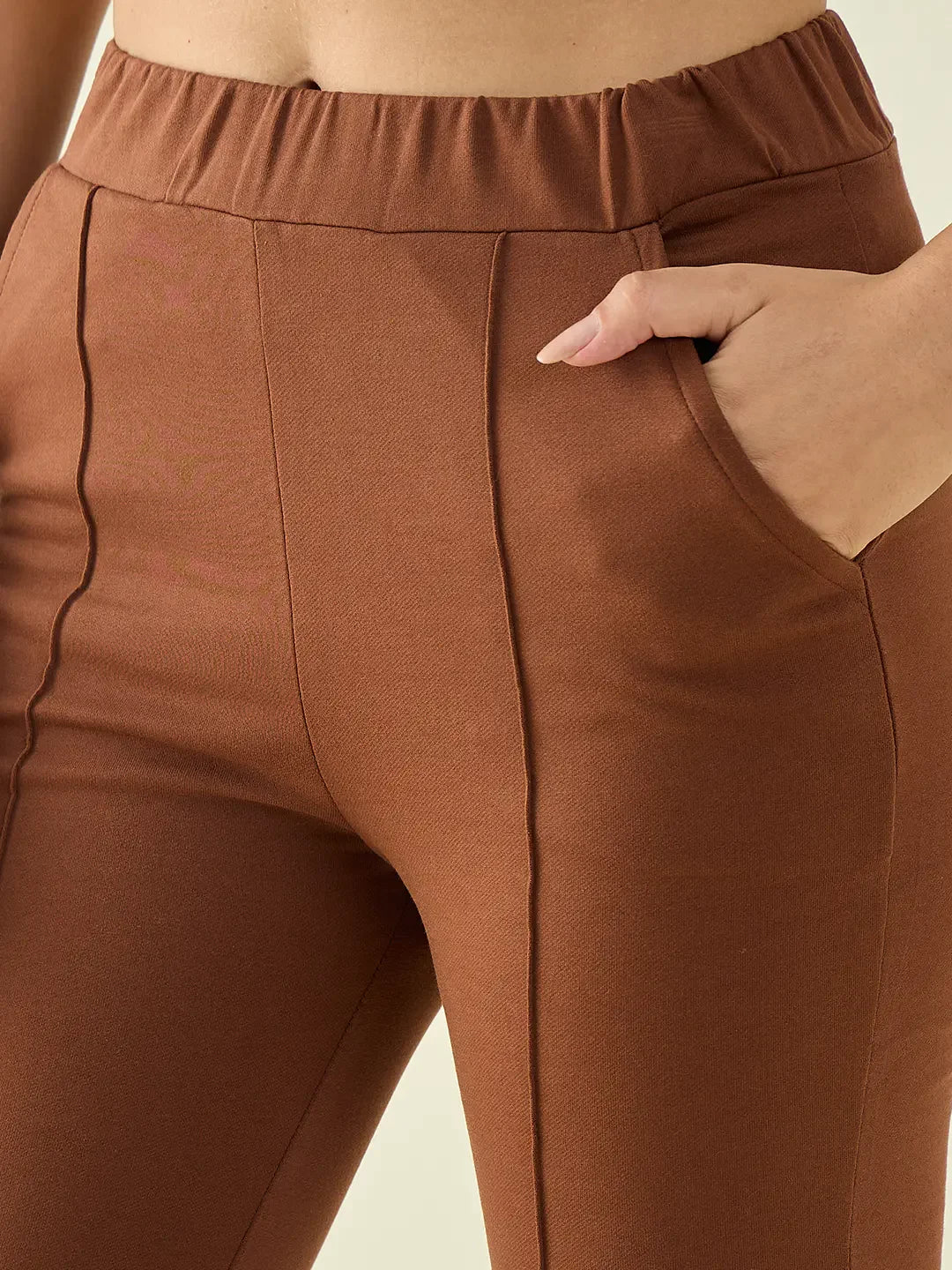 Close-up of a person wearing 98degreenorth Women’s Rust Flared Bootcut Cotton Stretchable Trousers, hand in pocket.