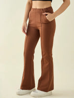 Wearing 98degreenorth Women’s Rust Flared Bootcut Trousers, white shoes, and a black crop top on a plain background.