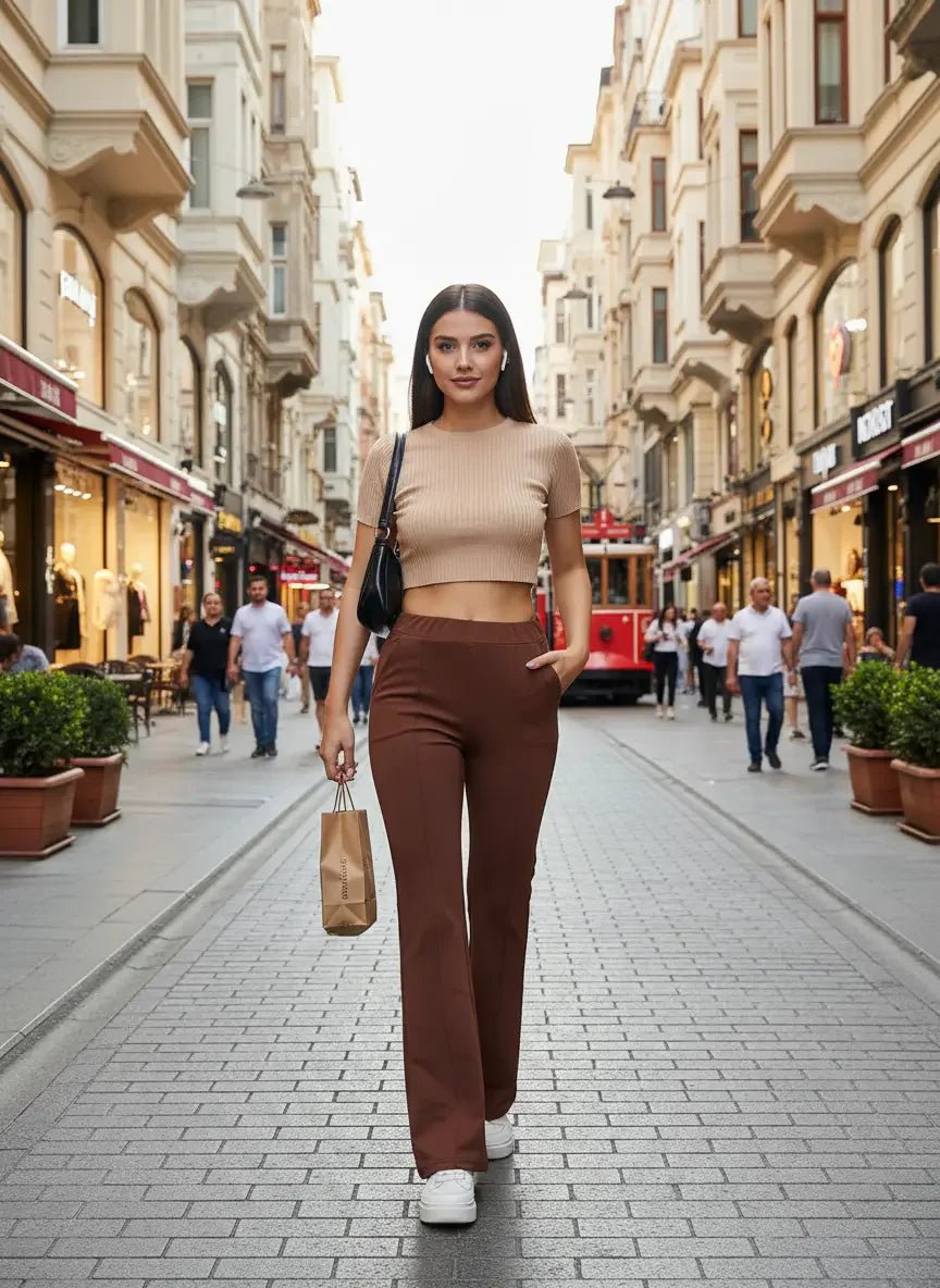 A woman in a beige crop top and 98degreenorth rust flared bootcut cotton stretchable trousers walks in the city.