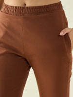 A person wears 98degreenorth Women’s Rust Flared Bootcut Stretchable Trousers with an elastic waistband, hand in pocket.