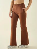 Person wearing 98degreenorth Women’s Rust Flared Fit Bootcut Pants, black crop top, silver sneakers, plain background.