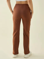 A person in 98degreenorth Women’s Rust Straight Fit Cotton Stretchable Trousers, white shoes, and a white top, viewed from behind.