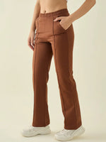 A woman wears 98degreenorth rust straight fit cotton stretchable trousers, posing against a plain background.