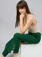 Woman in beige tank and 98degreenorth Smiley Green Flared Bootcut Sweatpants with side slit looks at the camera.