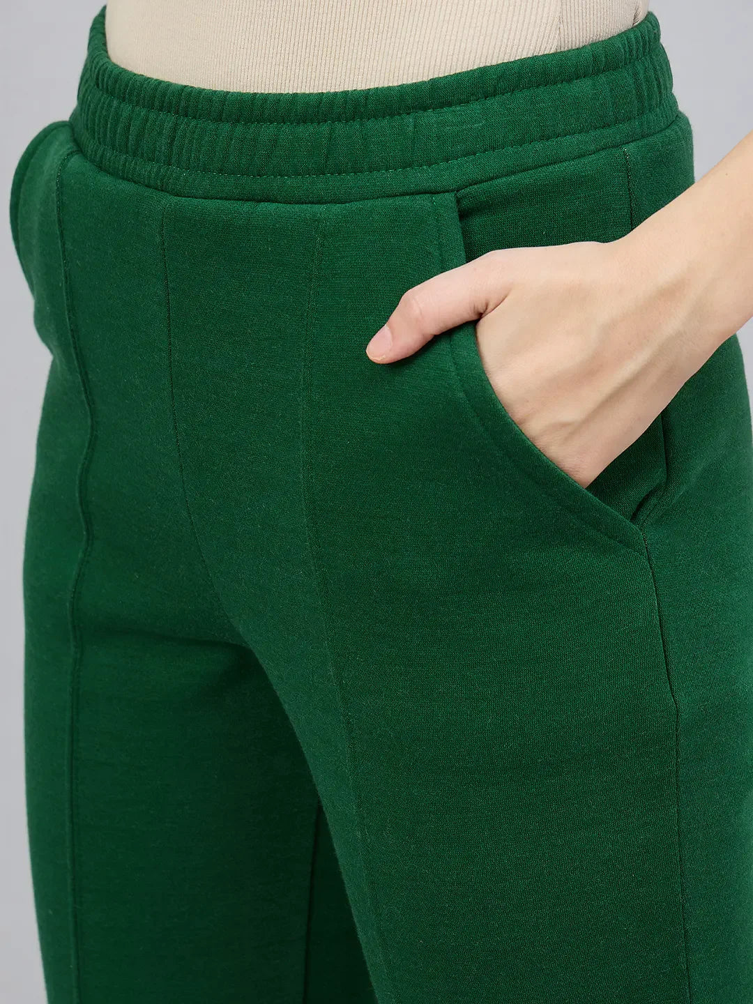 Model wears 98degreenorth Women’s Smiley Green Flared Bootcut Sweatpants, hand in right pocket, waist to mid-thigh.