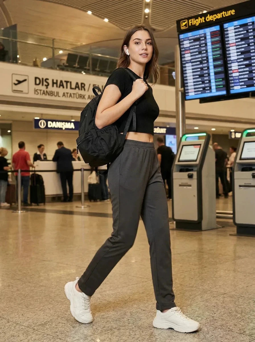 A woman in 98degreenorth Women's Straight Fit Cotton Trackpants in Charcoal walks through an airport.