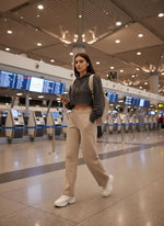 A woman in minimalist style wears 98degreenorth’s Women’s Straight Fit Fleece Sweatpants in Almond at the airport.