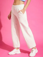 Person wears 98degreenorth Women’s Straight Fit Fleece Sweatpants in Butter and white sneakers, on a pink background.