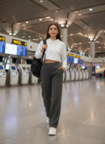 A woman wears 98degreenorth Women's Straight Fit Fleece Sweatpants in Olive, walking through an airport with a backpack.