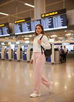 A woman in 98degreenorth Women’s Straight Fit Fleece Sweatpants in Pink Melange stands at an airport terminal.