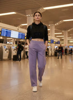 A woman in 98degreenorth’s violet straight fit fleece sweatpants walks confidently through an airport terminal.