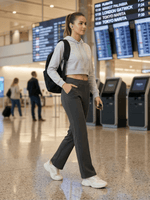 A woman in a gray hoodie and 98degreenorth’s Premium Pintuck Trousers walks through an airport terminal.