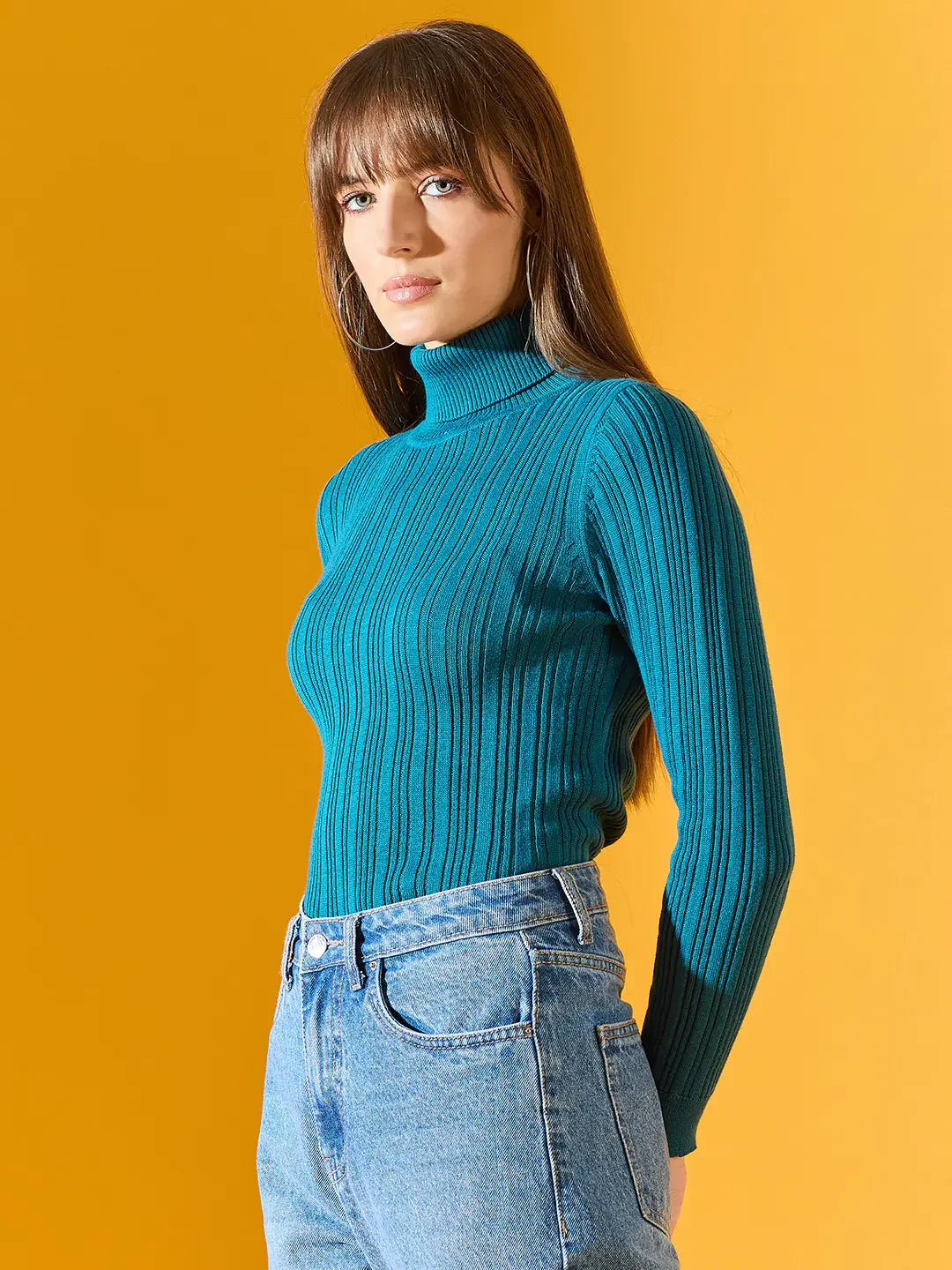 Woman in a 98degreenorth teal blue ribbed turtleneck sweater, showcasing stylish winter wear in India against yellow.