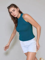 Woman in a 98degreenorth teal ribbed halter neck sleeveless knit top, posing against a light gray background.