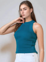 A woman models the 98degreenorth Women’s Teal Ribbed Halter Neck Sleeveless Knit Top with white pants against a neutral background.