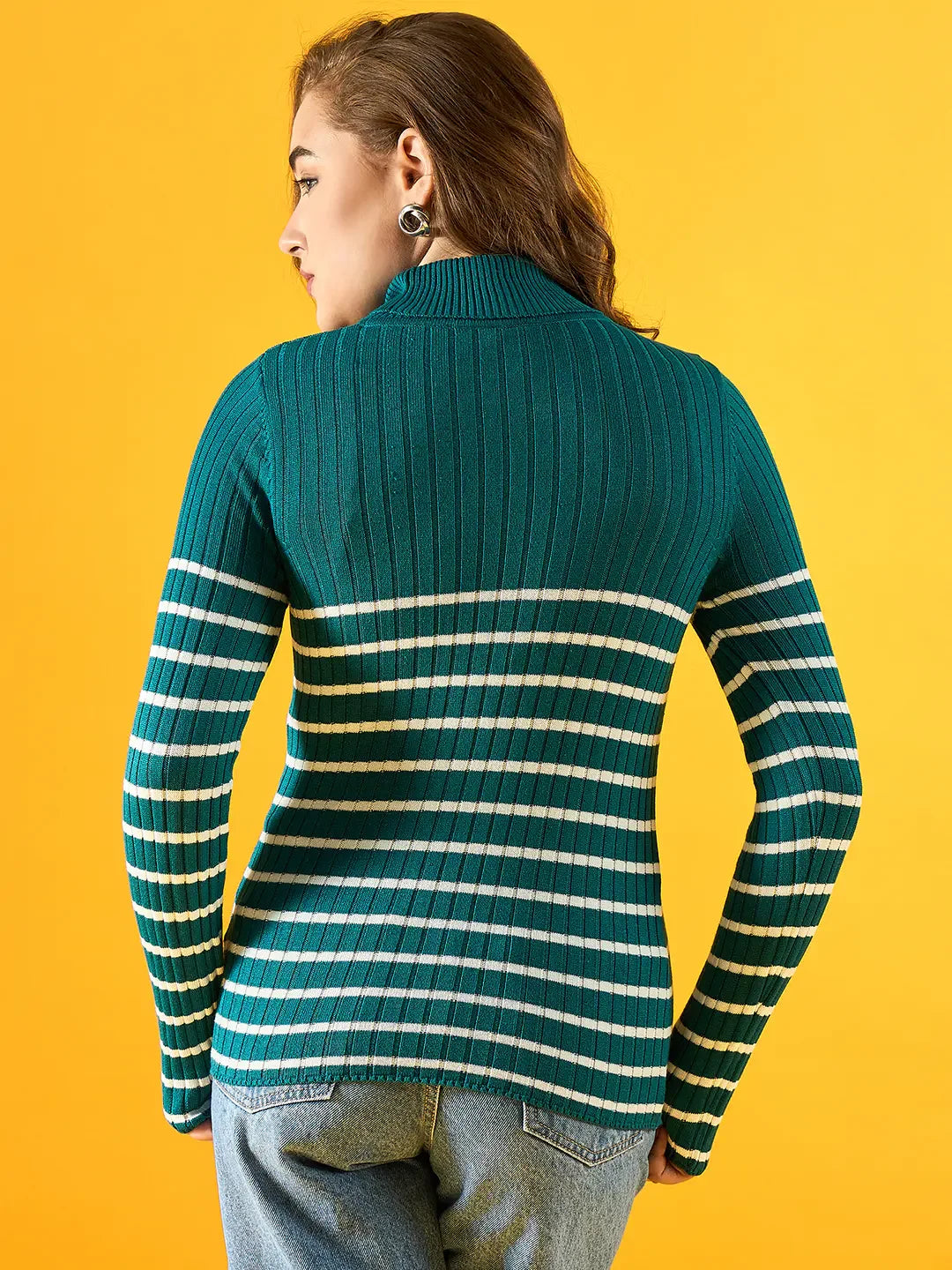 Woman in a 98degreenorth teal ribbed knit turtleneck sweater, facing away on a bright yellow background.