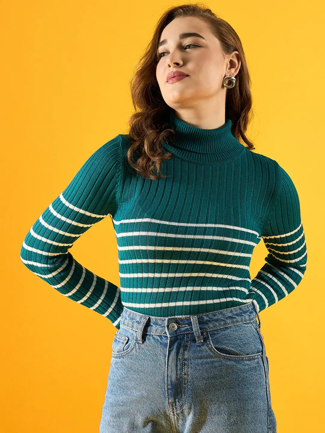 Woman in 98degreenorth’s teal ribbed knit turtleneck sweater stands against a yellow background, looking to the side.