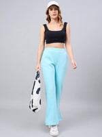 Woman in a black crop top, 98degreenorth turquoise flared bootcut sweatpants, white sneakers, cap, and a tote bag.