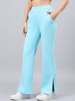 Woman in 98degreenorth turquoise flared bootcut sweatpants with side slit, white sneakers, and black crop top, sideways.