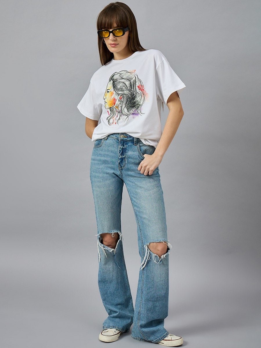 Woman in sunglasses, 98degreenorth Womens Typography Cotton T-shirt, ripped jeans & white sneakers stands by gray wall.
