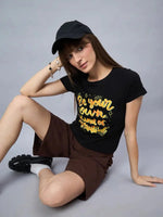 Woman in a black cap and brown shorts wears a 98degreenorth street-style typography print cotton t-shirt.