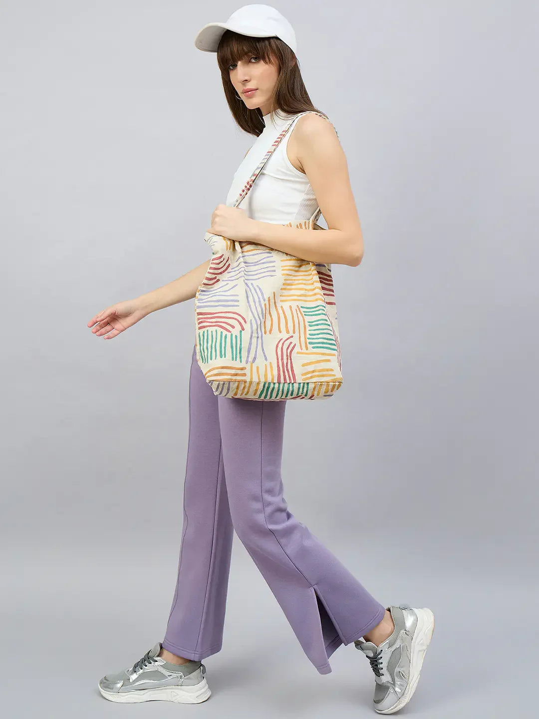 Woman in a white cap, sleeveless top, and 98degreenorth Violet Flared Bootcut Sweatpants with Side Slit, carrying a tote.