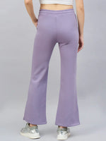A person wears 98degreenorth Women’s Violet Flared Bootcut Sweatpants with side slit, seen from the back on a gray background.