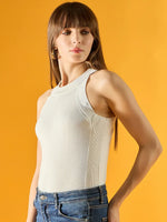 Woman in a 98degreenorth Women’s White Ribbed Halter Neck Sleeveless Knit Top and blue jeans against a yellow background.