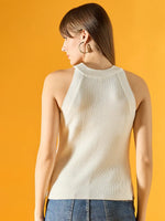 Woman with straight brown hair wears a 98degreenorth white ribbed halter neck knit tank top, standing by a yellow background.