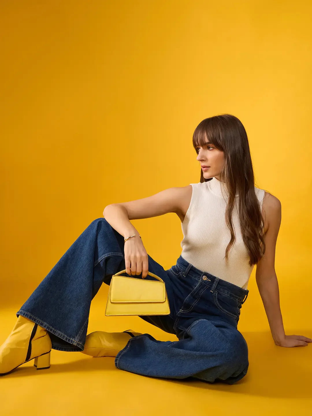 Woman wears 98degreenorth Women’s White Ribbed High Neck Sleeveless Knit Top with wide-leg jeans, yellow boots, and purse.