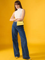 A woman in a 98degreenorth white ribbed high neck knit tank, wide-leg jeans, and yellow shoes holds a yellow handbag.