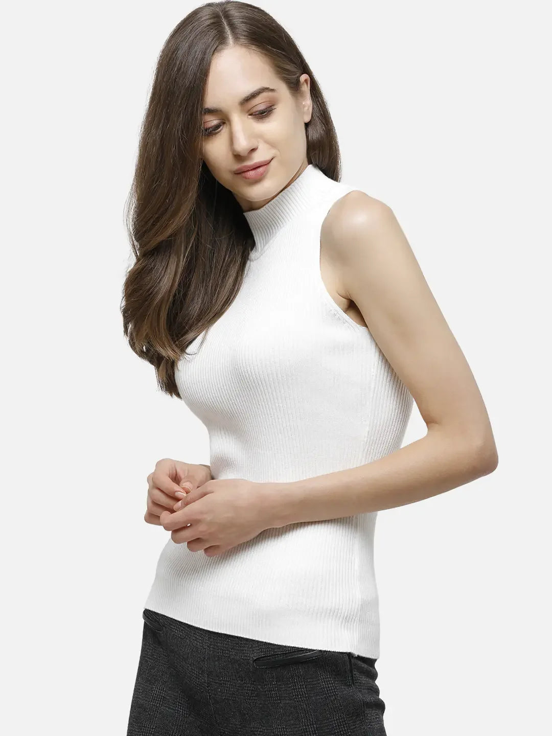 Woman wears 98degreenorth Women’s White Ribbed High Neck Sleeveless Knit Top, standing against a plain background.