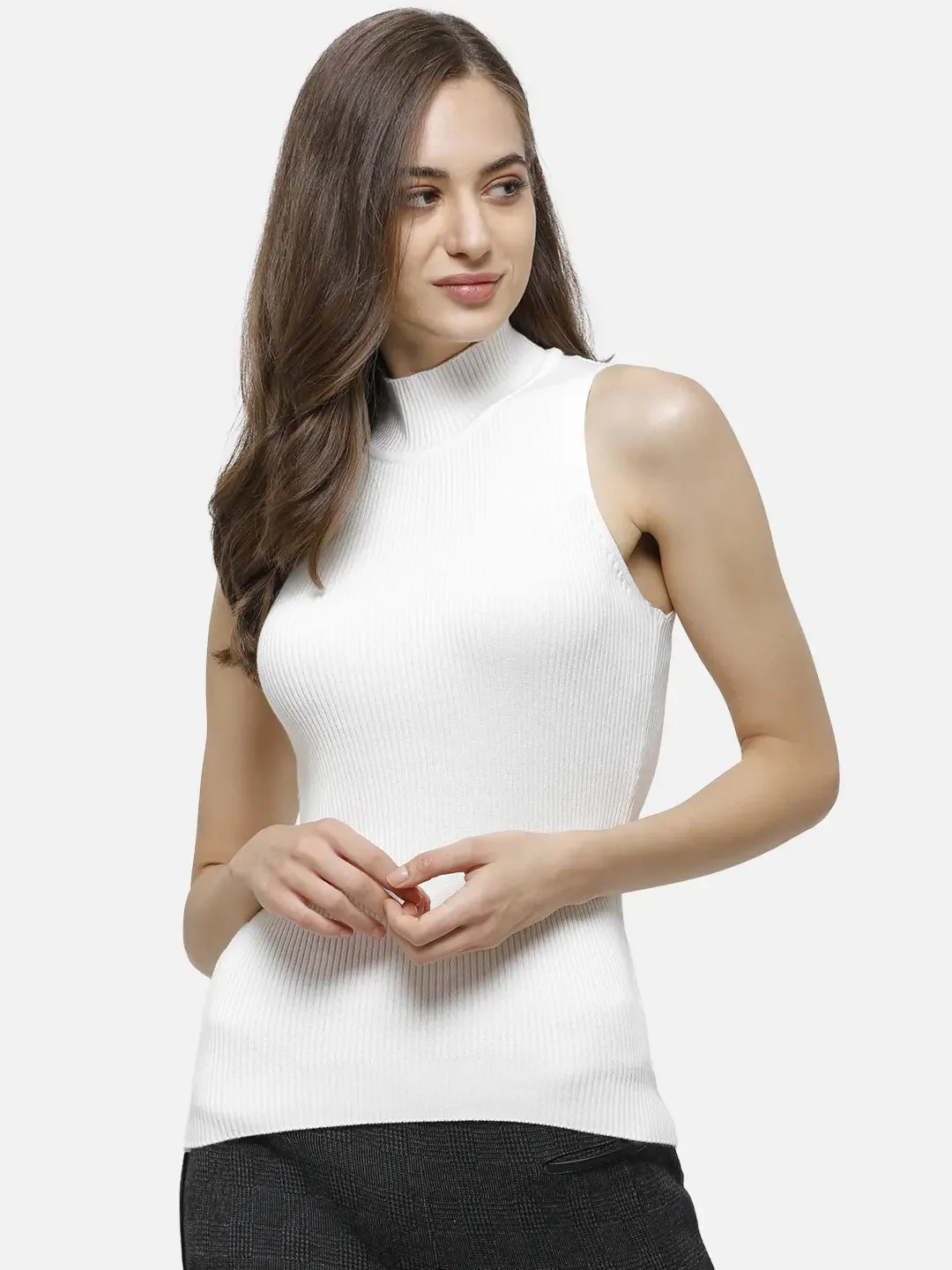 Woman in a 98degreenorth white ribbed high neck sleeveless knit top and dark pants, against a plain light background.
