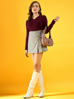 Woman in a 98degreenorth Women’s Wine Ribbed Collar Sweater, gray mini skirt, white boots, and pink purse on yellow bg.